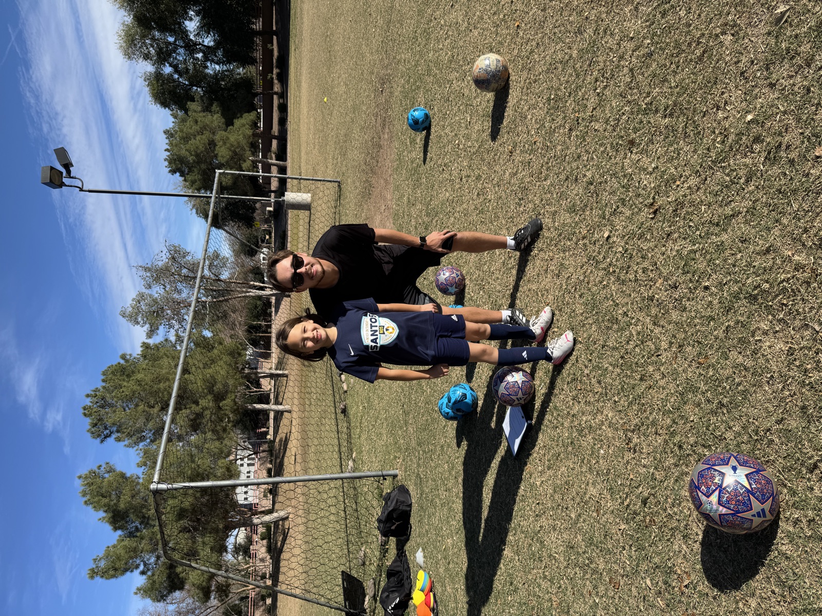 Coach David Fales kneeling beside a young player by the goal after a private soccer training session in Mesa, Arizona.