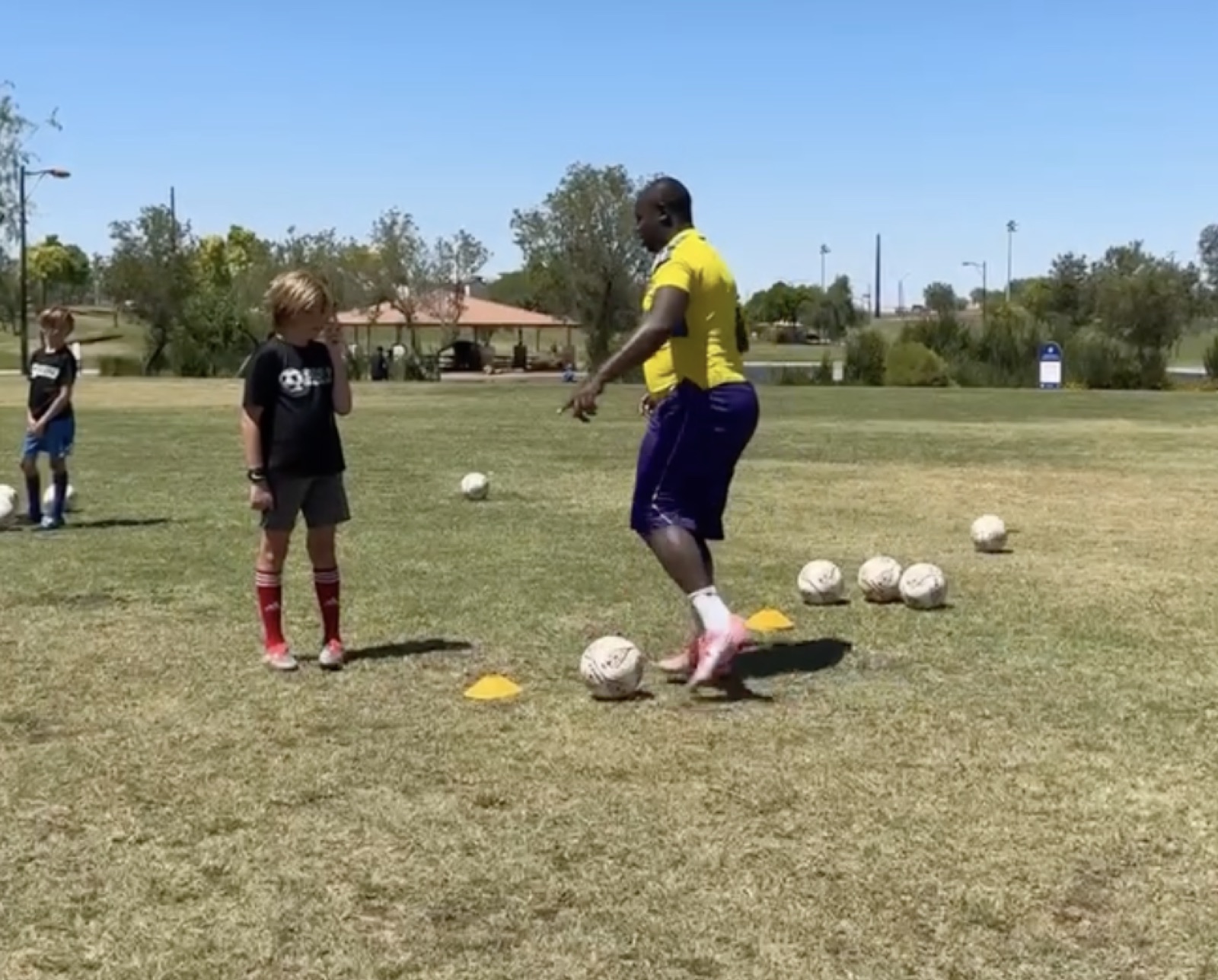 Young player dribbling toward Coach David Fales during a training drill.