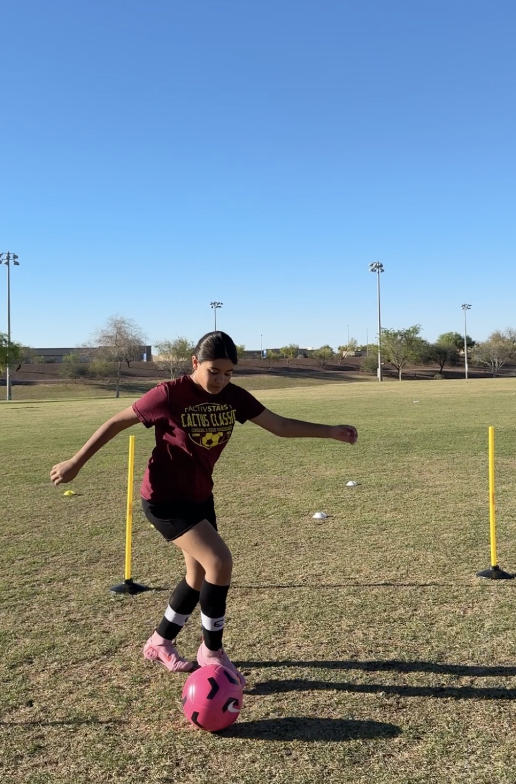 Youth player dribbling through slalom poles during a technical training drill.