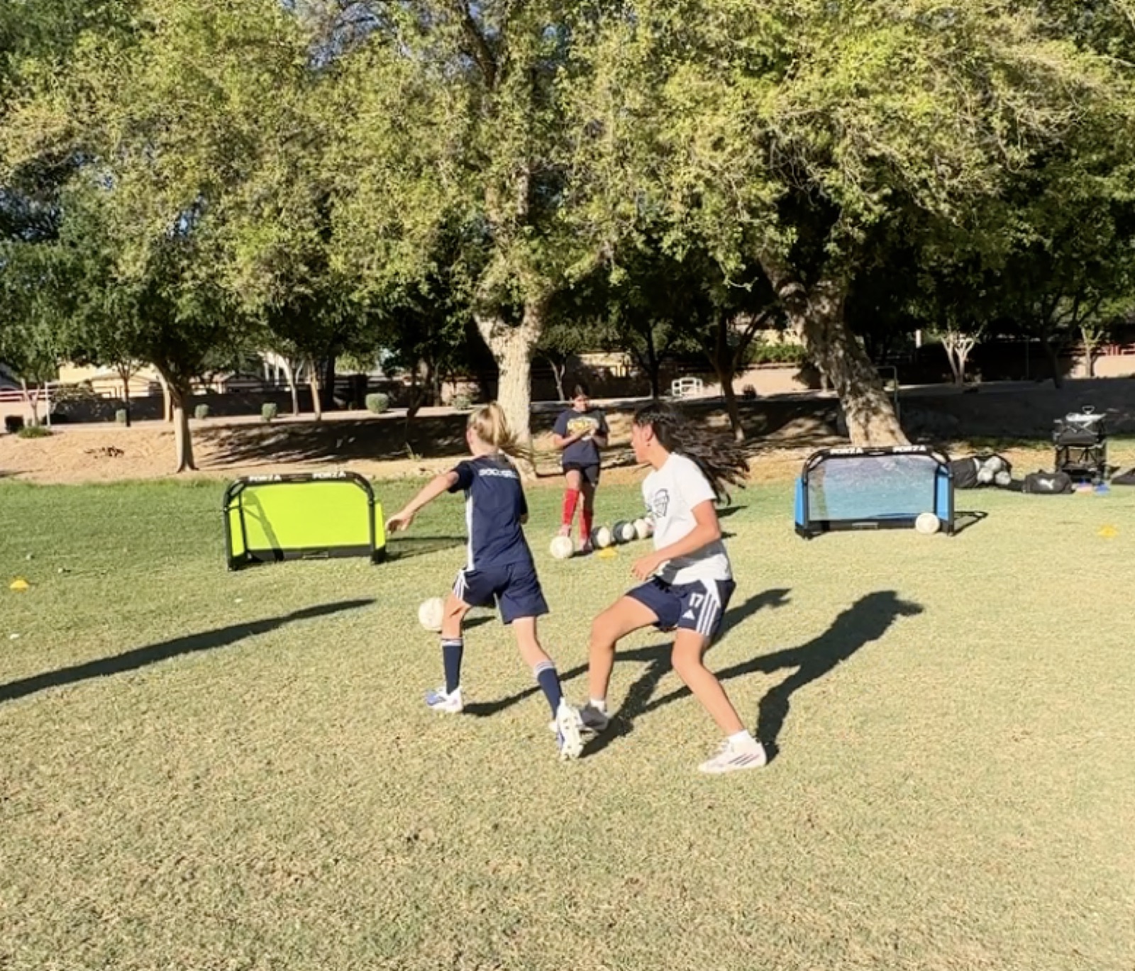 Two young players racing while dribbling soccer balls during training.