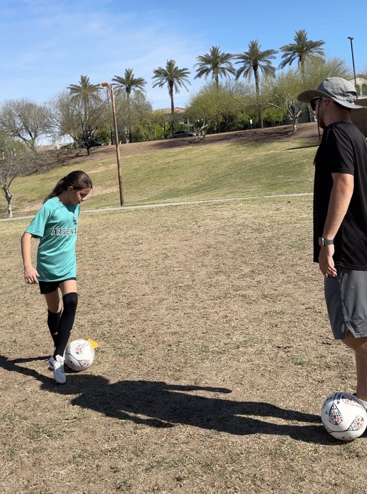 Young player dribbling a soccer ball across a grass field during a private training session.