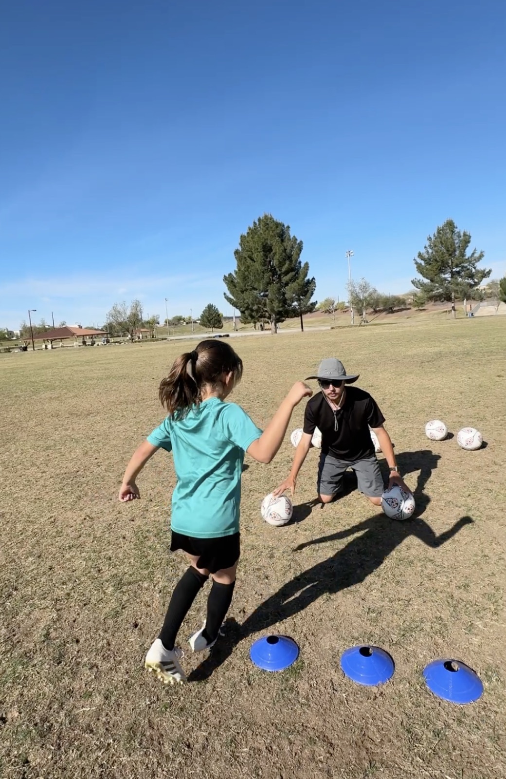 Young player dribbling a ball between training discs during a session.