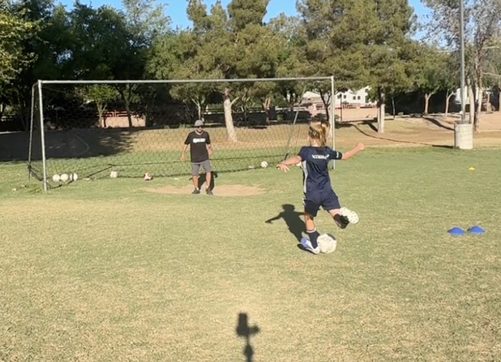 Youth player striking a soccer ball during a shooting drill.
