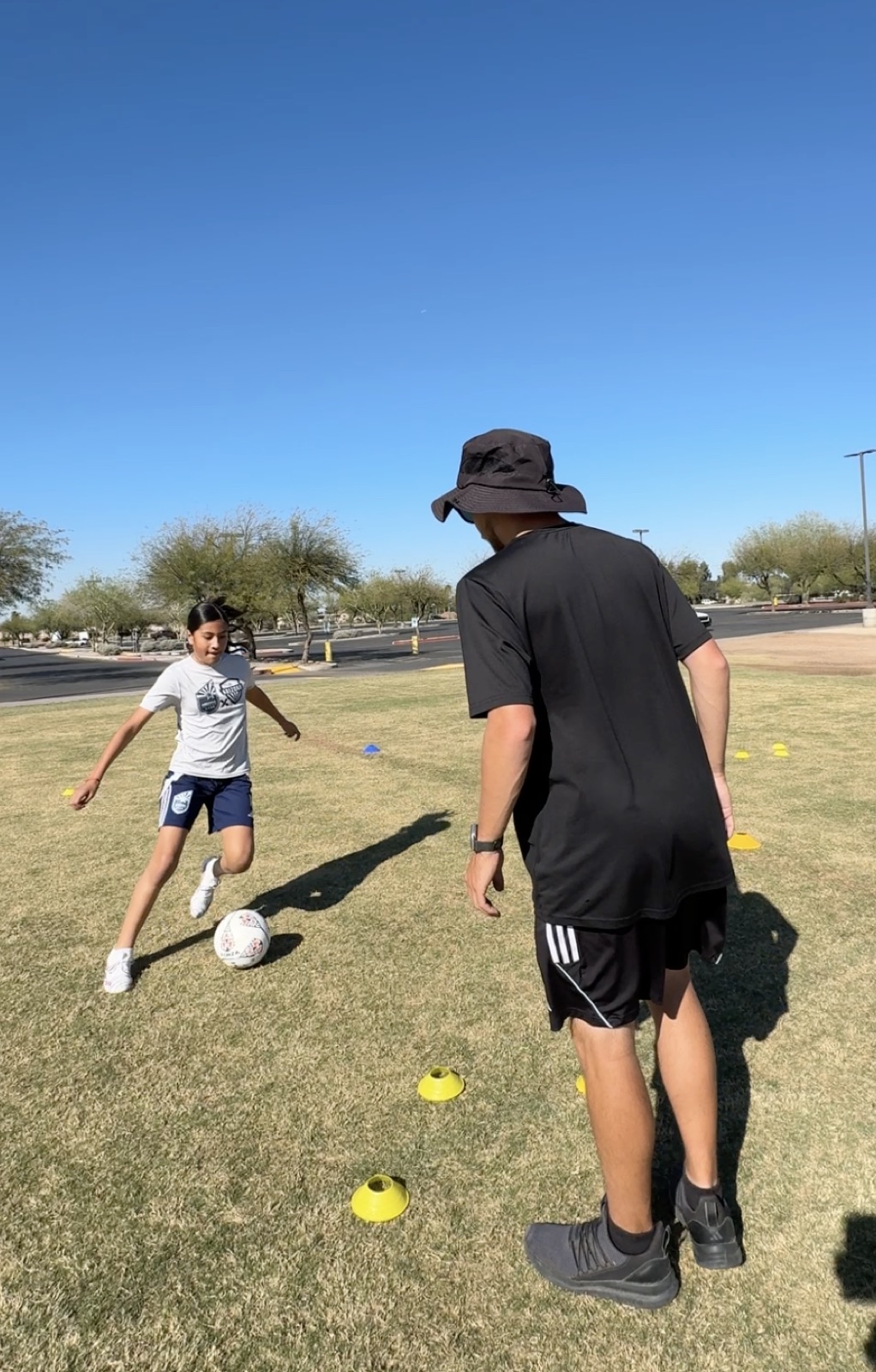 Coach David Fales coaching a young player through dribbling reps on the field.