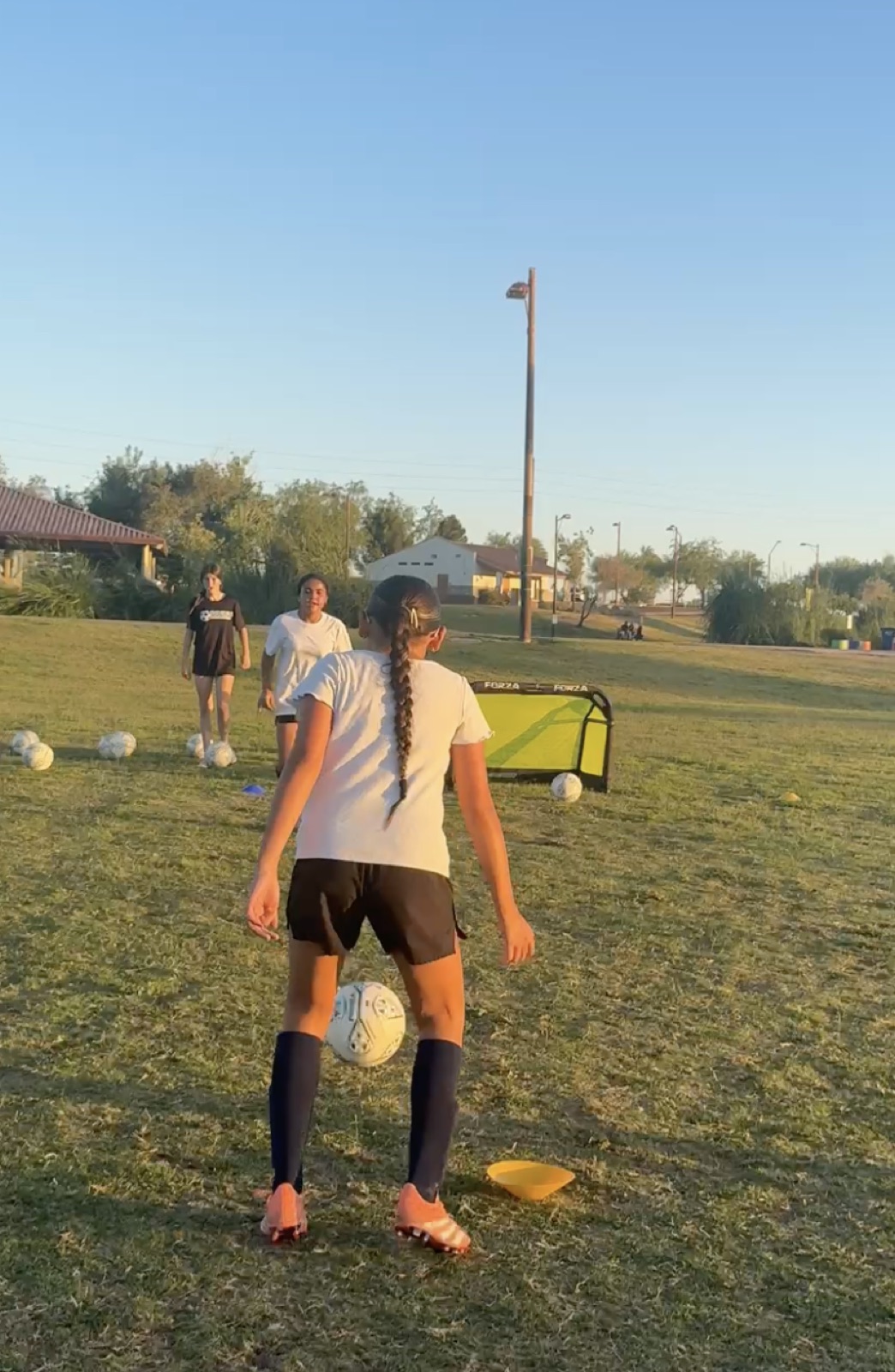 Young player shielding a soccer ball during an evening training session.