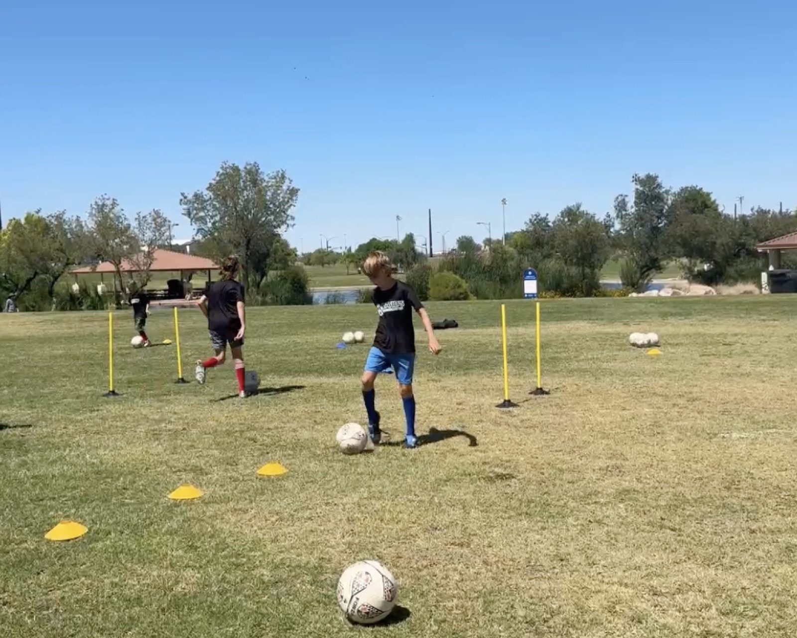 Youth player dribbling through poles during a slalom drill.