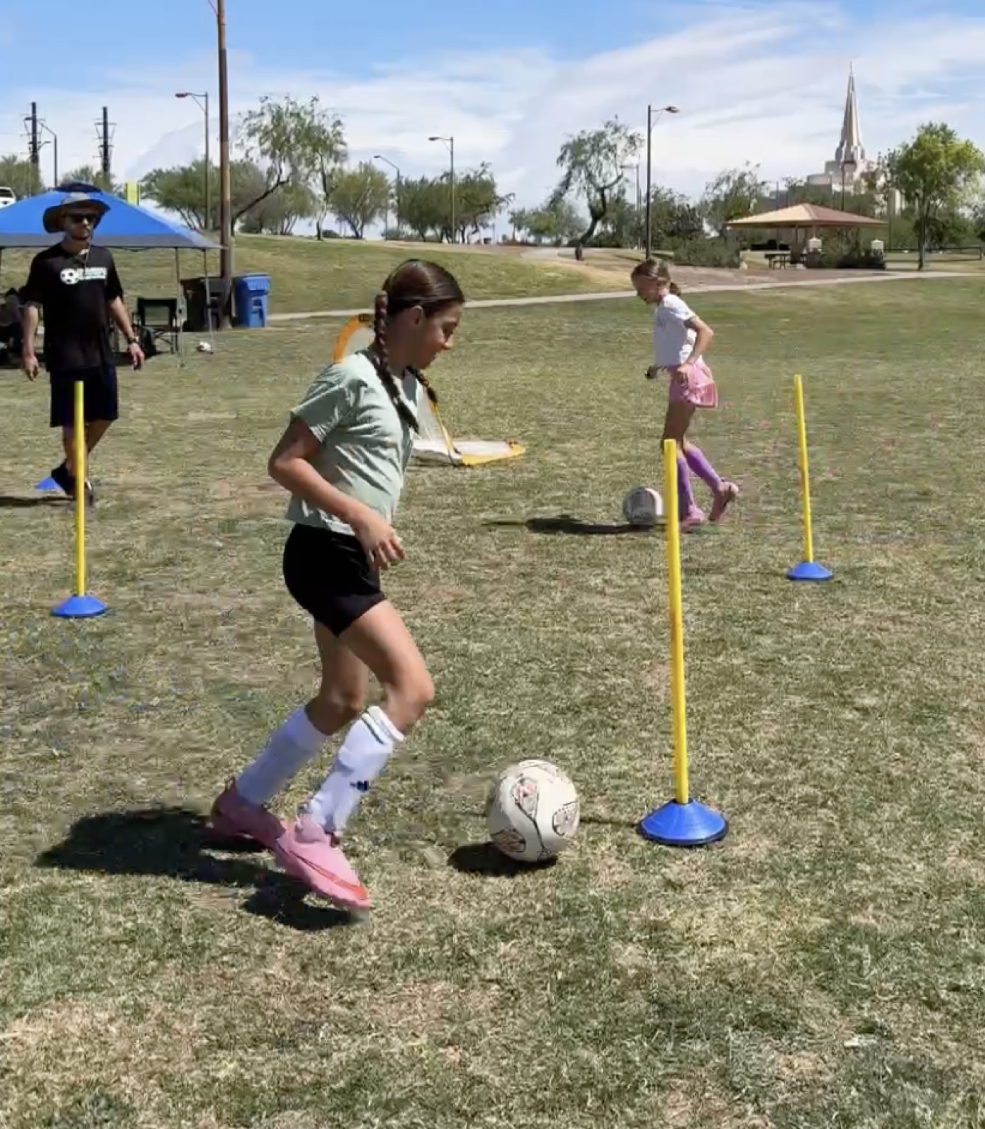 Young player dribbling at speed through slalom poles.