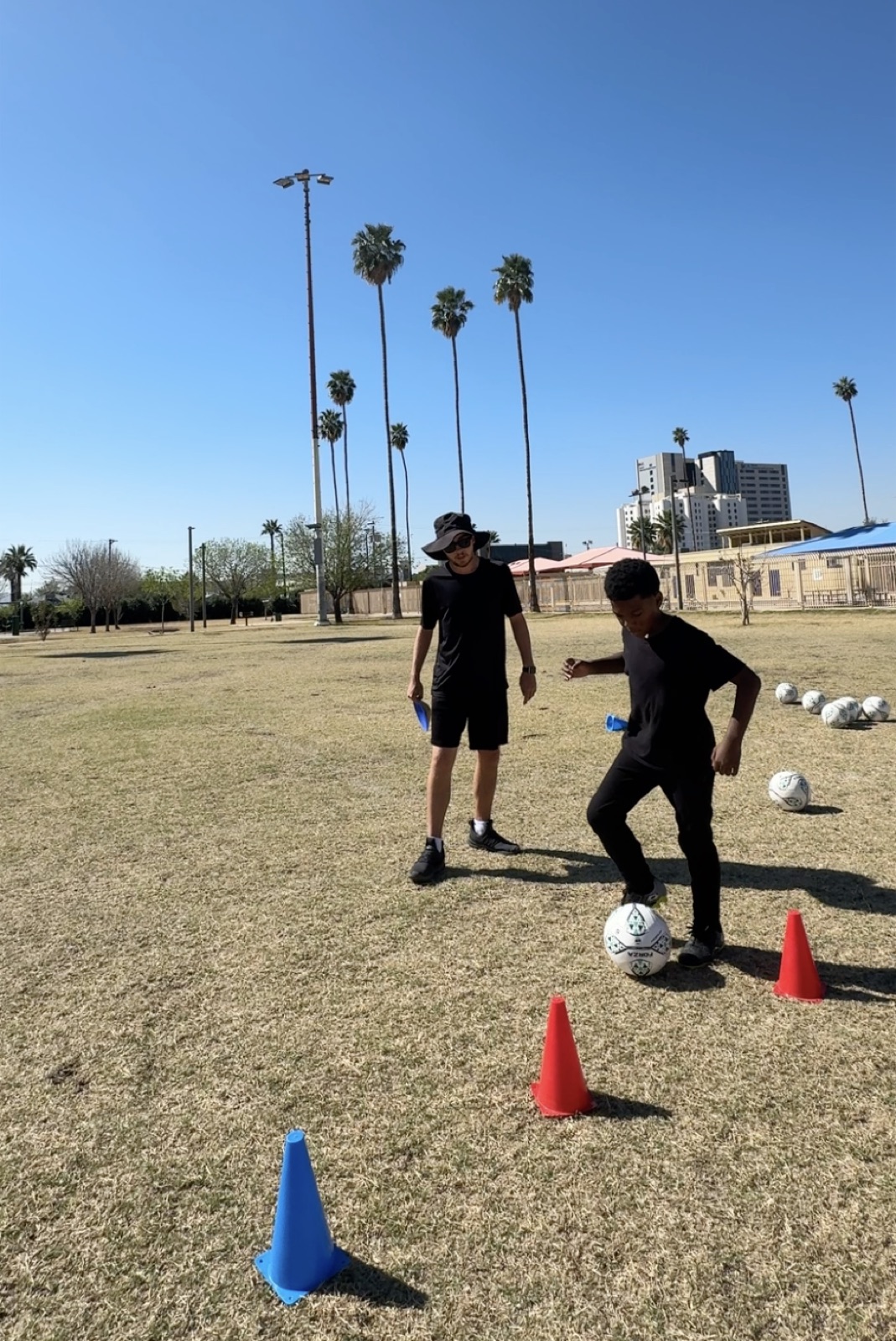 Coach David Fales guiding a player through a cone dribbling drill.